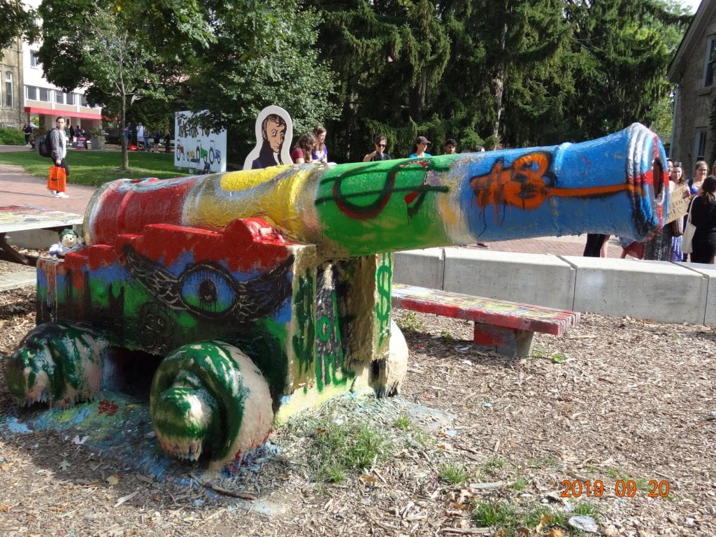 Avogadro cutup behind a colourfully painted historical cannon