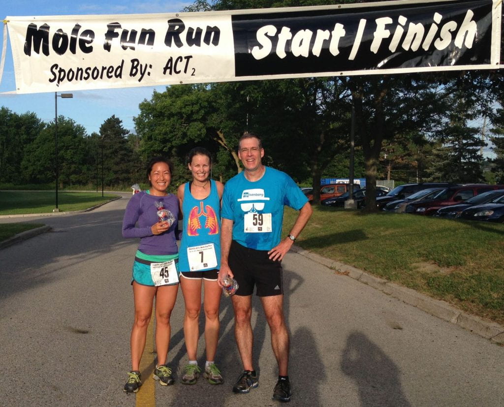 three runners under the mole fun run sign with their running bid
