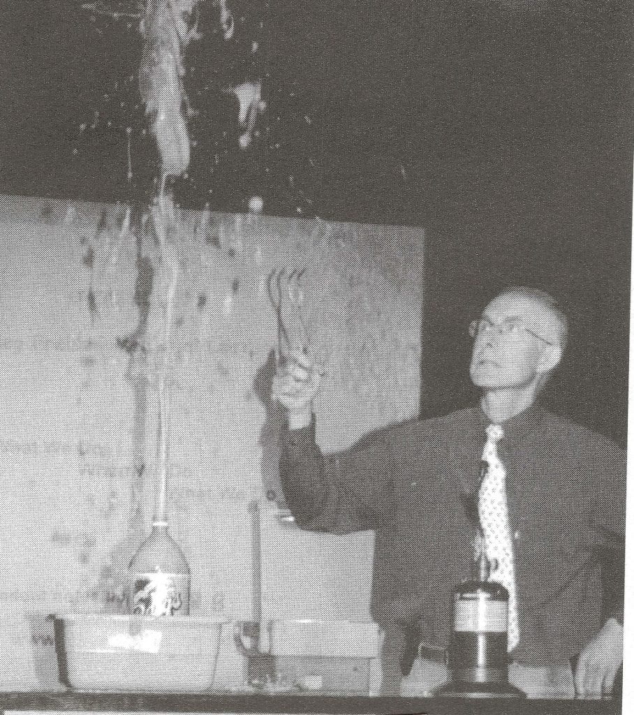 Doug De La Matter with a large soda pop bottle that is spraying foam upwards