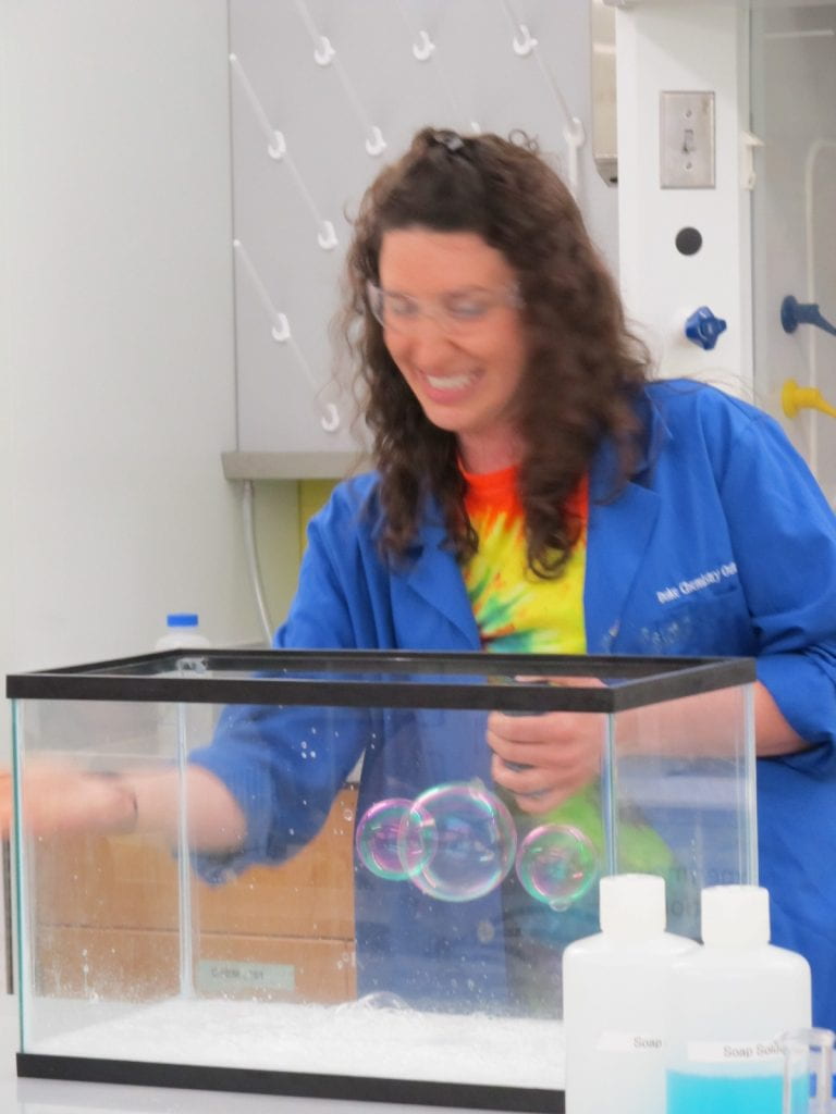 Jill Sterling in front of an empty aquarium with floating bubbles