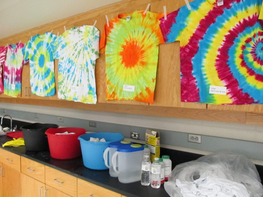 a lab with various colourful tie dyed T-shirts hung up along with buckets on the counters