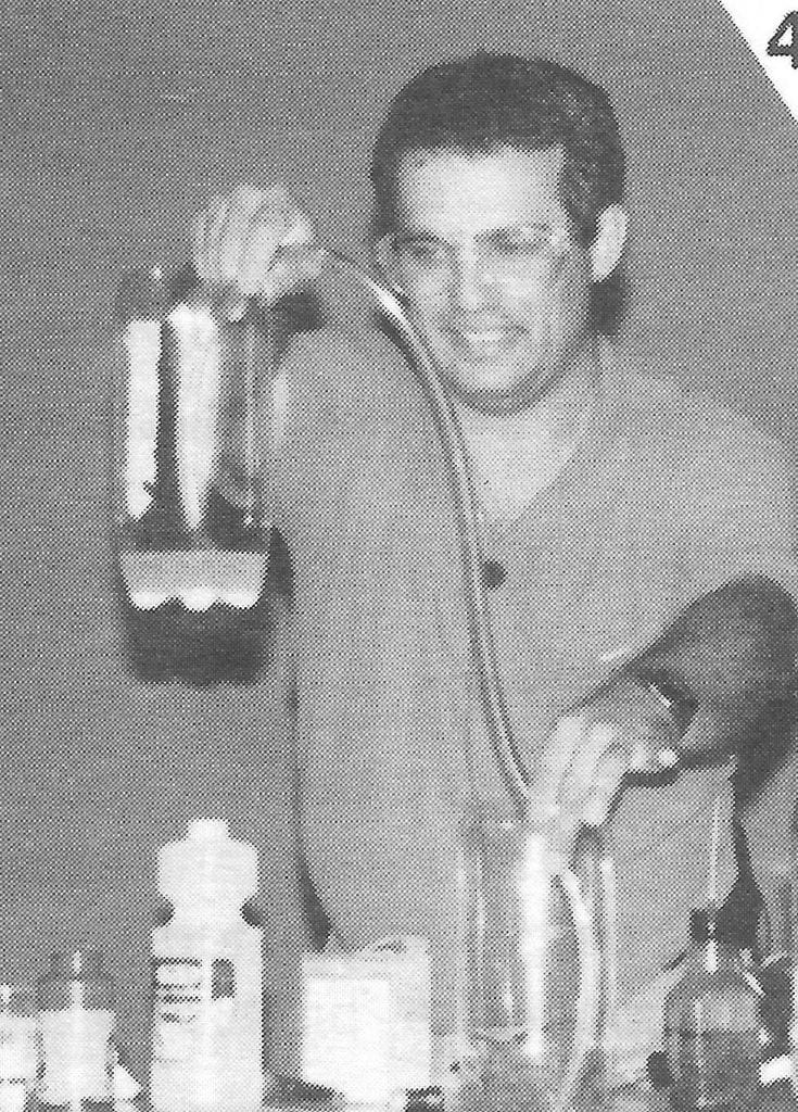Bob Becker holding a tube between two large pop bottles filled with water