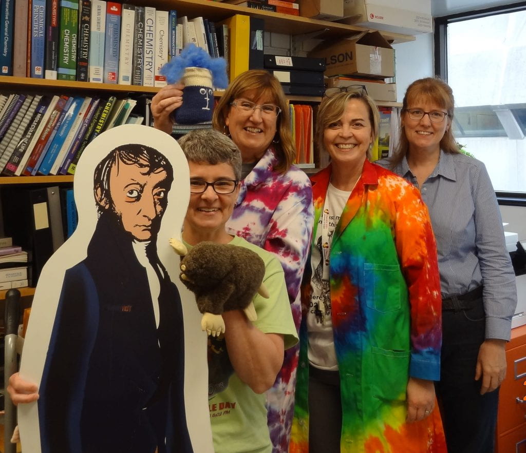 life-size cut out of Avogadro with Charlene Winchcombe-Forhan, Bonnie Lasby, Jean Hein and Lori Jones in an office setting