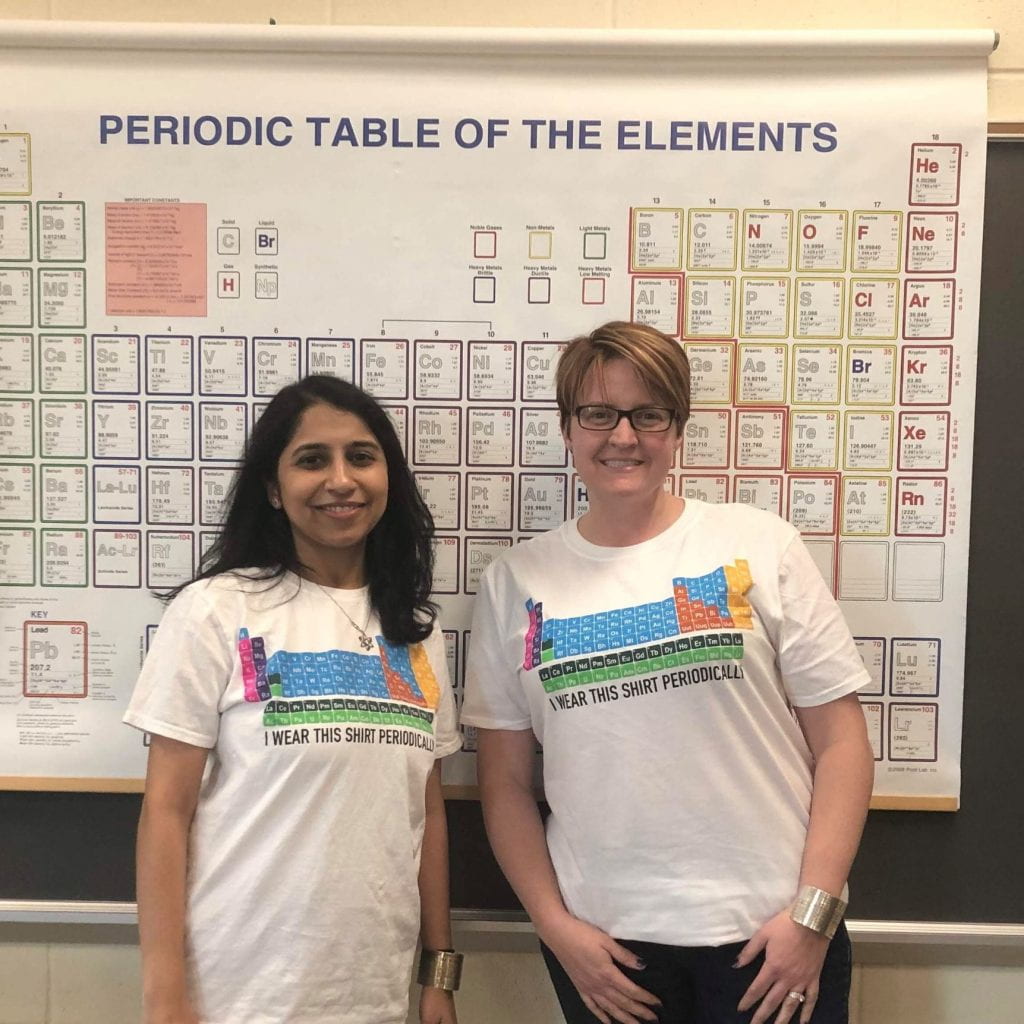 Anjana Iyer and Catherine Zavacki, chemistry teachers with periodic table t-shirts in front of a periodic table